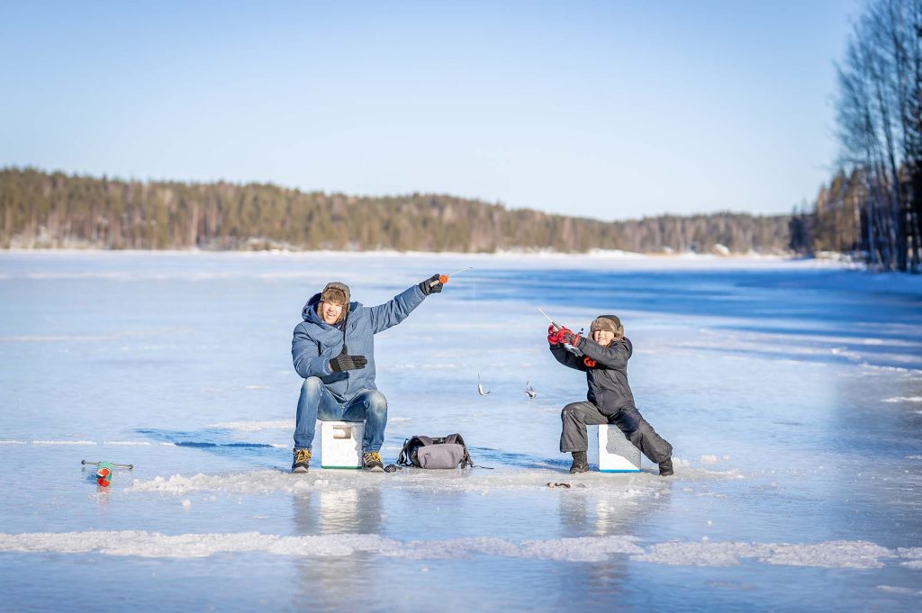 Father and son at winter fishing on frozen lake