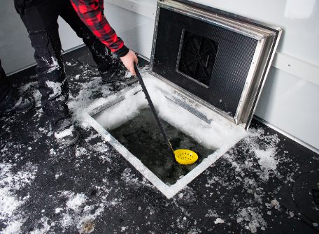 scooping out ice from skid house dark house
