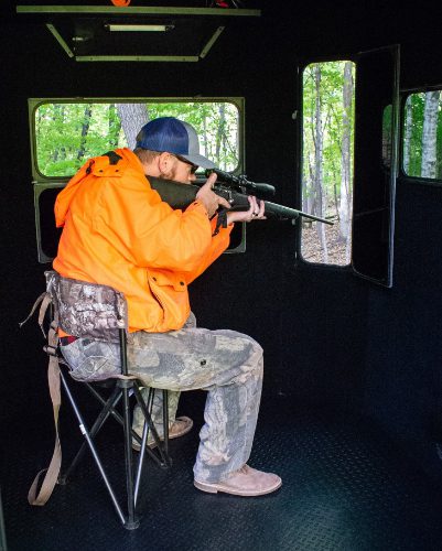 Hunter aiming through window of hunting blind