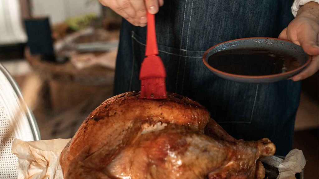 A man brushing a turkey with marinade